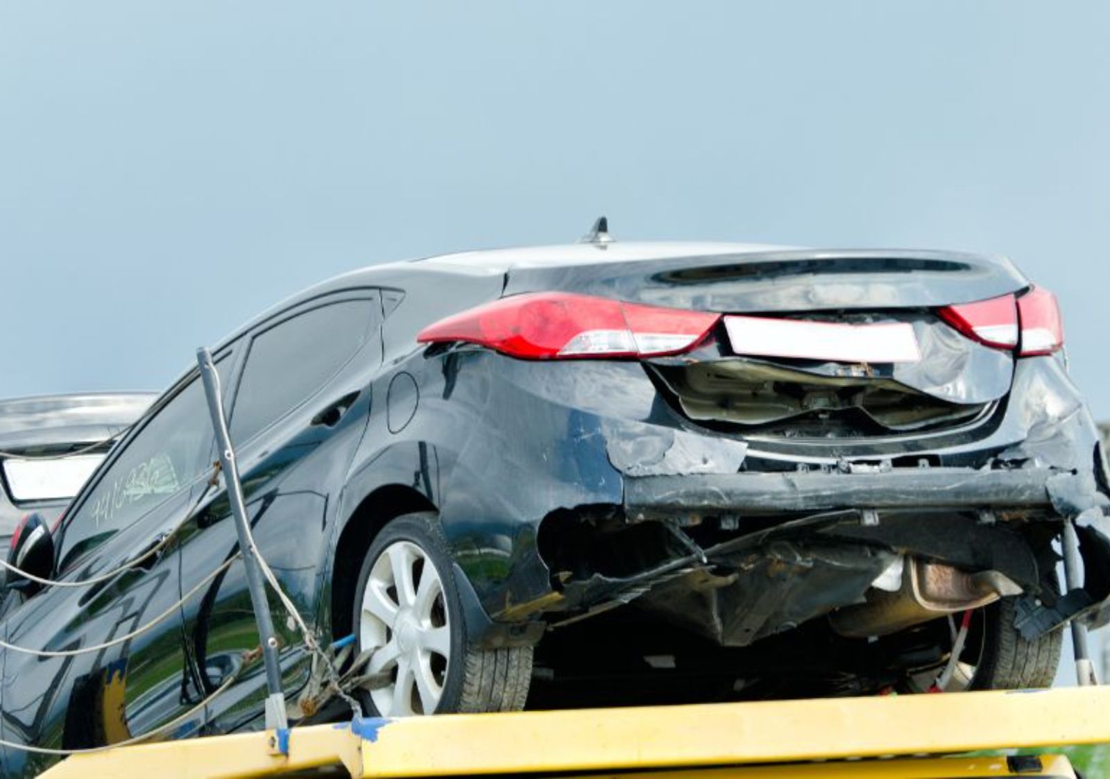 Damaged black sedan being towed for junk car removal in Deltona, FL