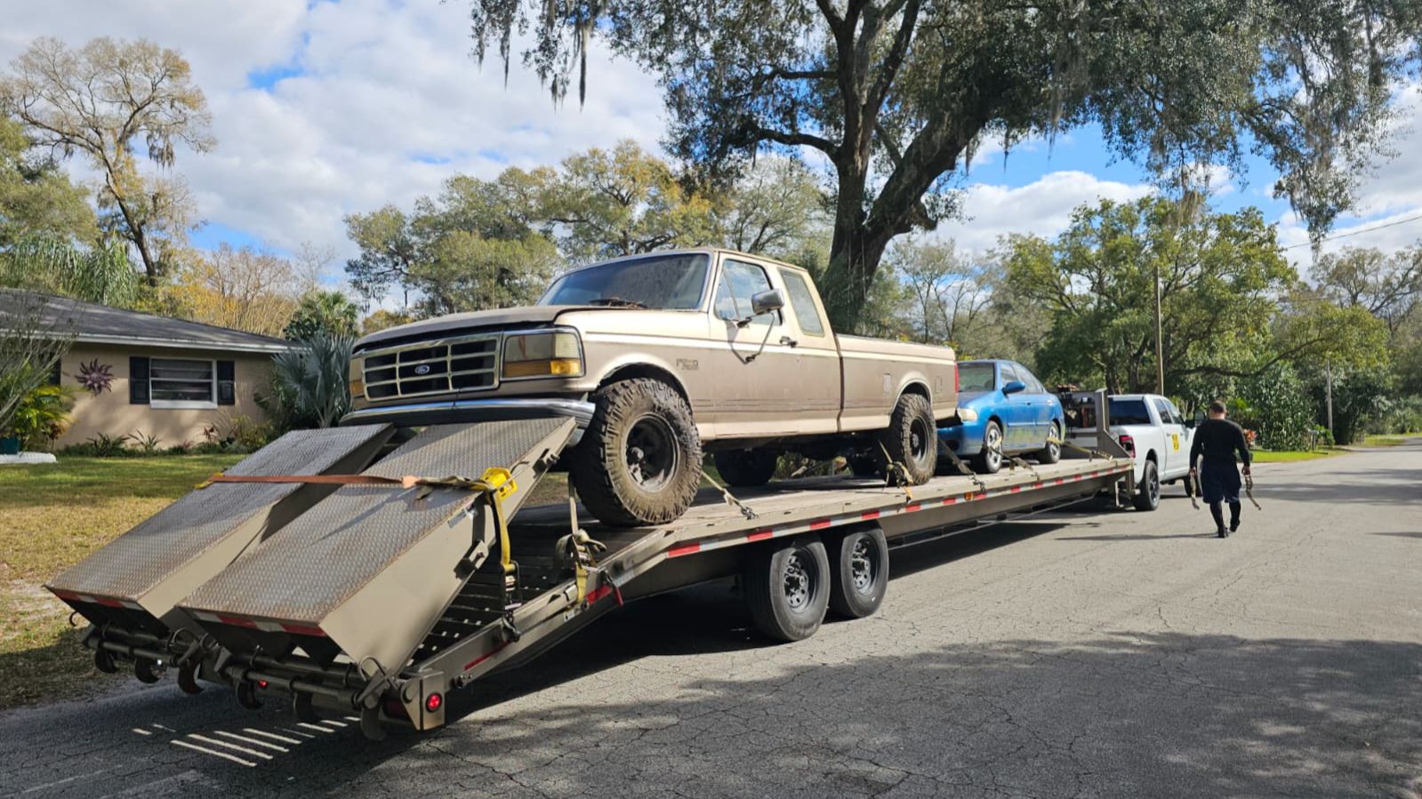 junk car buyers near me towing pickup truck on trailer in Central Florida