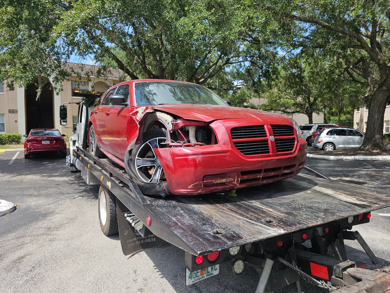 junk cars for cash pickup in Deltona FL with damaged red car on tow truck